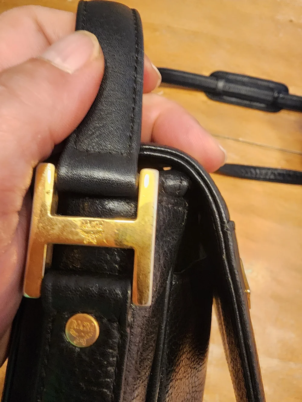 vintage MCM black pebbled leather studded crossbody bag featuring a front plaque